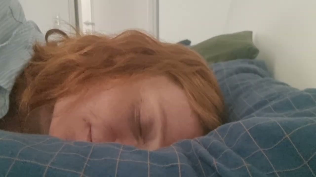 Lisi liegt mit geschlossenen Augen unter einer blau karierten Decke